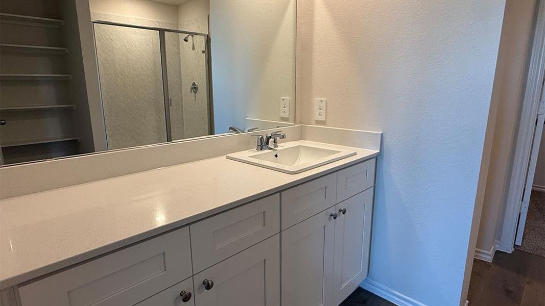 Vanity with a single undermount sink, quartz countertop, and white shaker-style cabinetry