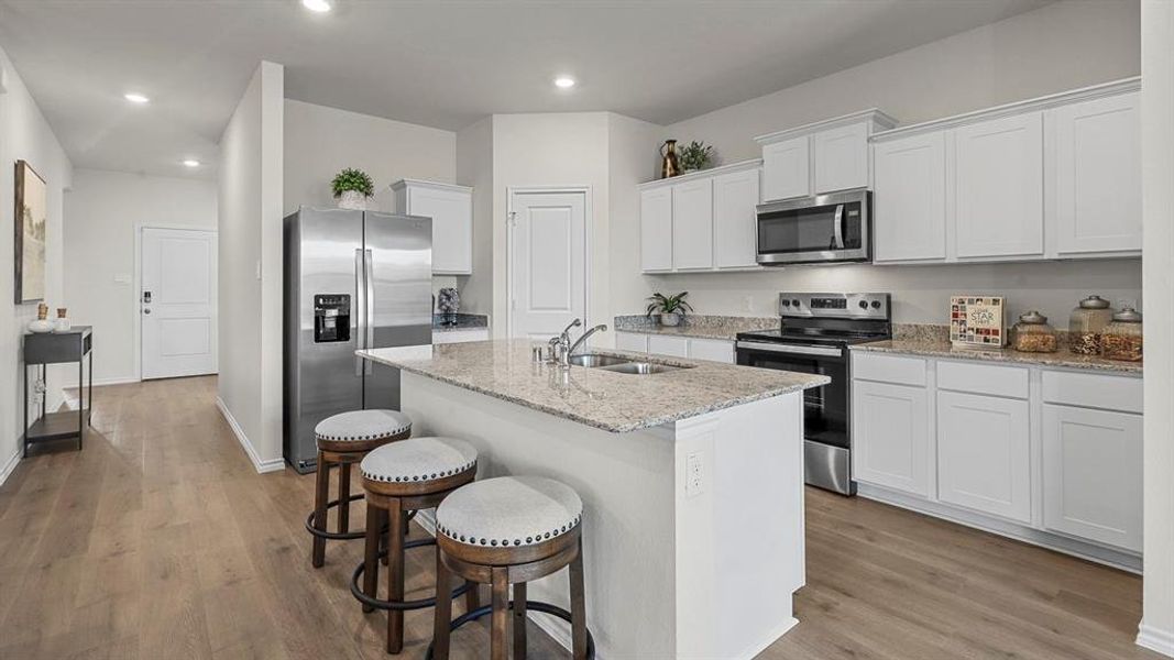 The kitchen features white cabinetry, stainless steel appliances, and granite countertops