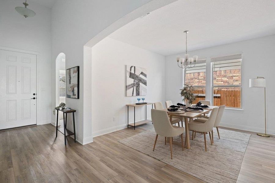 Dining room with arched walkways, light wood-style flooring, and a chandelier Dining room with arched walkways, light wood-style flooring, and a chandelier