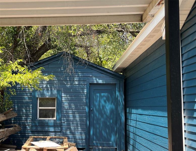 Detached outbuilding with teal horizontal siding and a gable roof