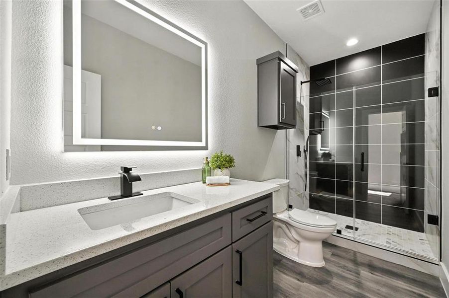 Full bath featuring a textured wall, a shower stall, vanity, and dark wood-style flooring Full bath featuring a textured wall, a shower stall, vanity, and dark wood-style flooring