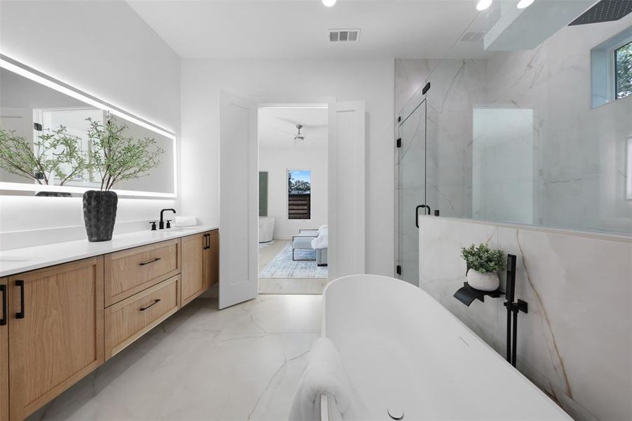Ensuite bathroom featuring a marble finish shower, double vanity, a freestanding tub, and recessed lighting