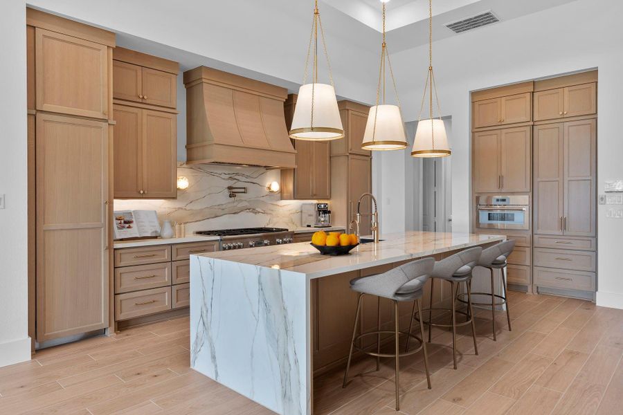 The gourmet kitchen features a large island and luxurious finishes as chosen by our award-winning design center. Representative image.