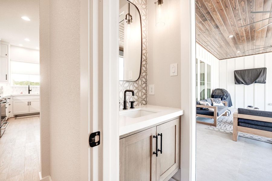 Half bathroom featuring vanity, recessed lighting, and tasteful backsplash