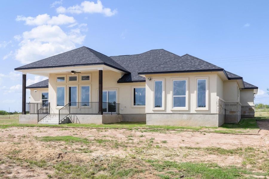 Back of house with a shingled roof, stucco siding, covered porch, and stone siding Back of house with a shingled roof, stucco siding, covered porch, and stone siding