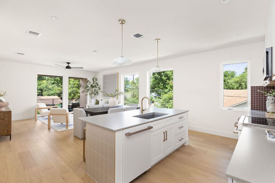 Sunlight streams through large windows into this modern, open-concept kitchen and living area. Sunlight streams through large windows into this modern, open-concept kitchen and living area.