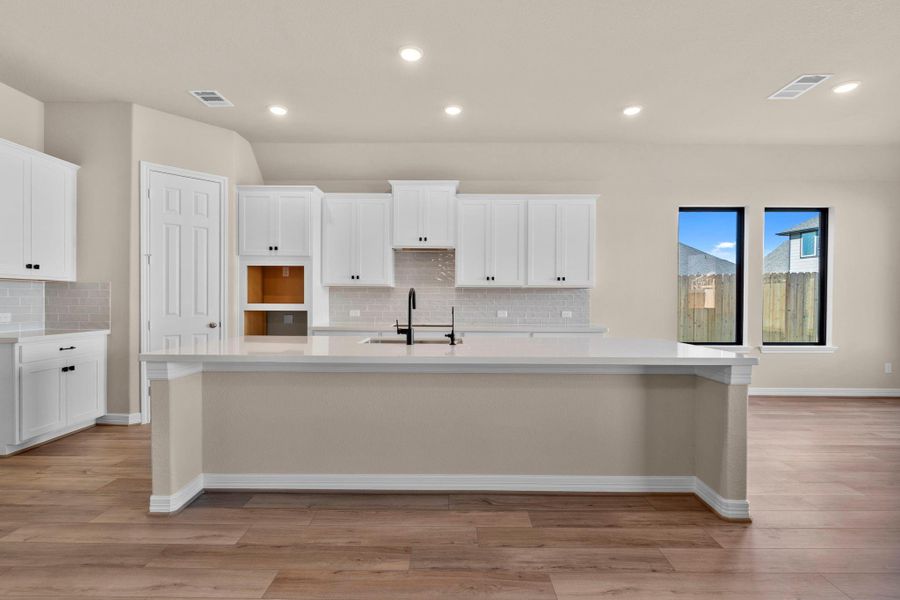 This light and bright kitchen features a large quartz island, white cabinets, a large sink overlooking your family room, recessed lighting, and beautiful backsplash. This light and bright kitchen features a large quartz island, white cabinets, a large sink overlooking your family room, recessed lighting, and beautiful backsplash.