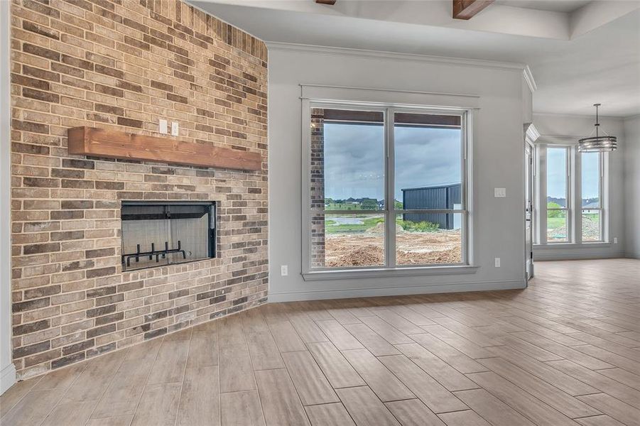 Unfurnished living room with light wood-type flooring, a fireplace, and crown molding