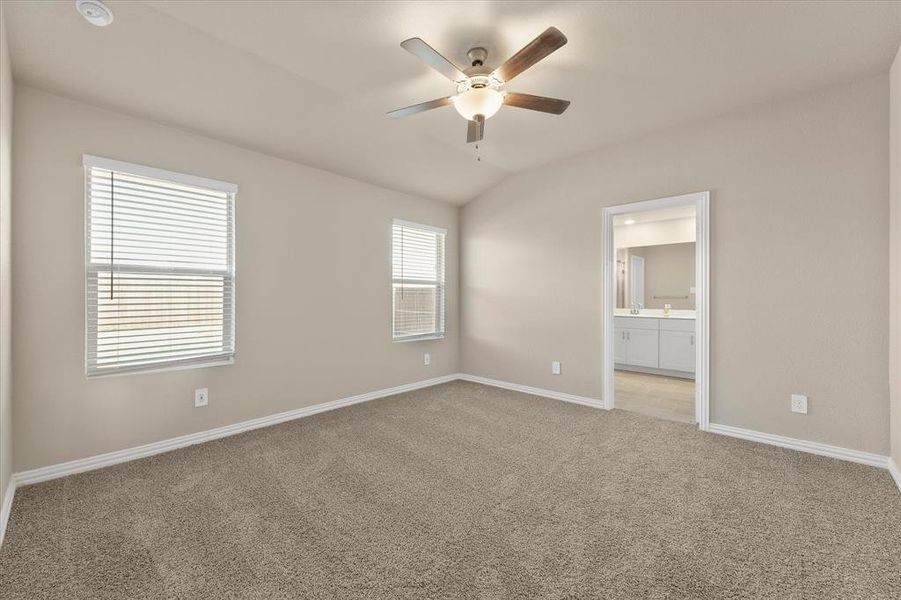 Unfurnished bedroom with light colored carpet, a ceiling fan, lofted ceiling, and connected bathroom Unfurnished bedroom with light colored carpet, a ceiling fan, lofted ceiling, and connected bathroom