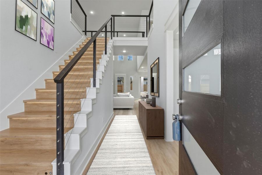 As you enter, the staircase to the left showcases luxury vinyl flooring, motion-sensor LED lighting on each step, and a sleek modern handrail.(virtual staging)