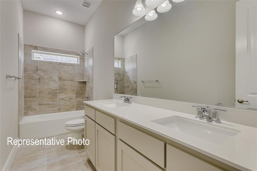 Bathroom featuring a dual vanity with white countertops and integrated sinks, chrome faucets, and an expansive wall mirror