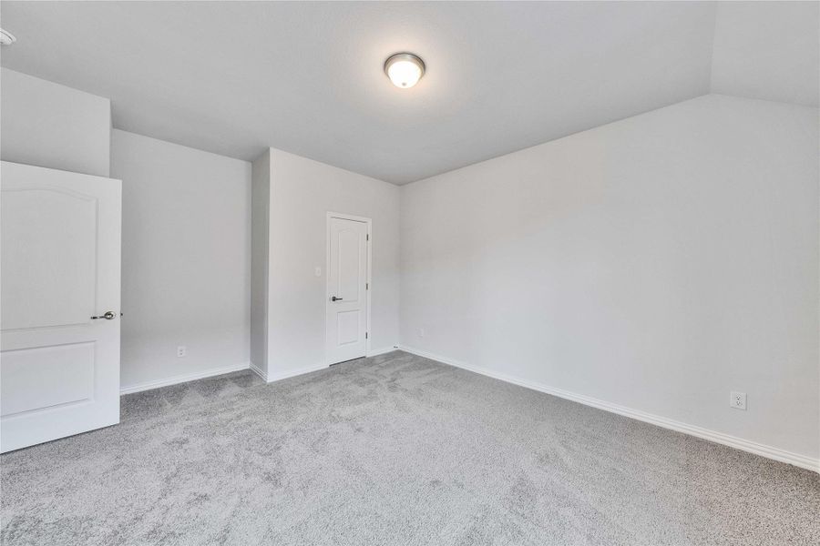 Unfurnished bedroom with carpet, baseboards, and lofted ceiling Unfurnished bedroom with carpet, baseboards, and lofted ceiling