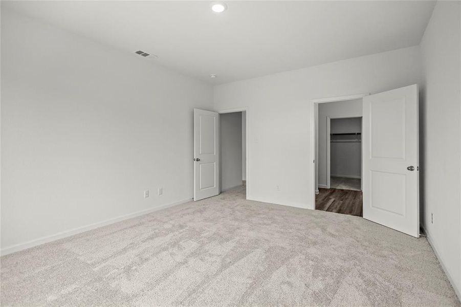 Primary bedroom with expansive layout and direct access to en-suite bath.