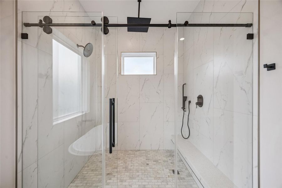 Full-height tilework and matte black fixtures bring contrast and texture into the walk-in shower. The oversized glass enclosure keeps the space feeling open and connected to the rest of the bath. Full-height tilework and matte black fixtures bring contrast and texture into the walk-in shower. The oversized glass enclosure keeps the space feeling open and connected to the rest of the bath.
