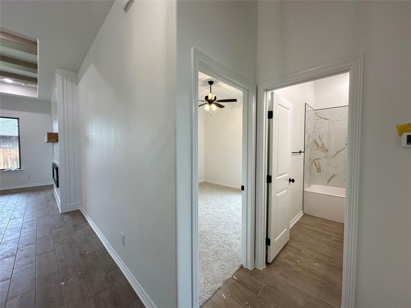 Hallway featuring wood-finish tile flooring, crisp white walls, and bright white baseboards