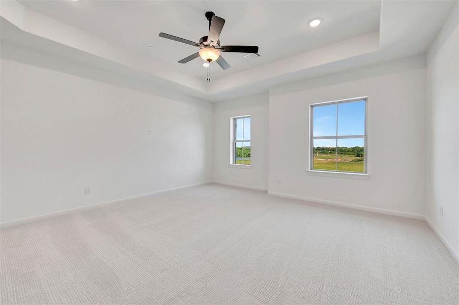 Spacious room featuring a tray ceiling, recessed lighting, and a ceiling fan with integrated light fixture Spacious room featuring a tray ceiling, recessed lighting, and a ceiling fan with integrated light fixture