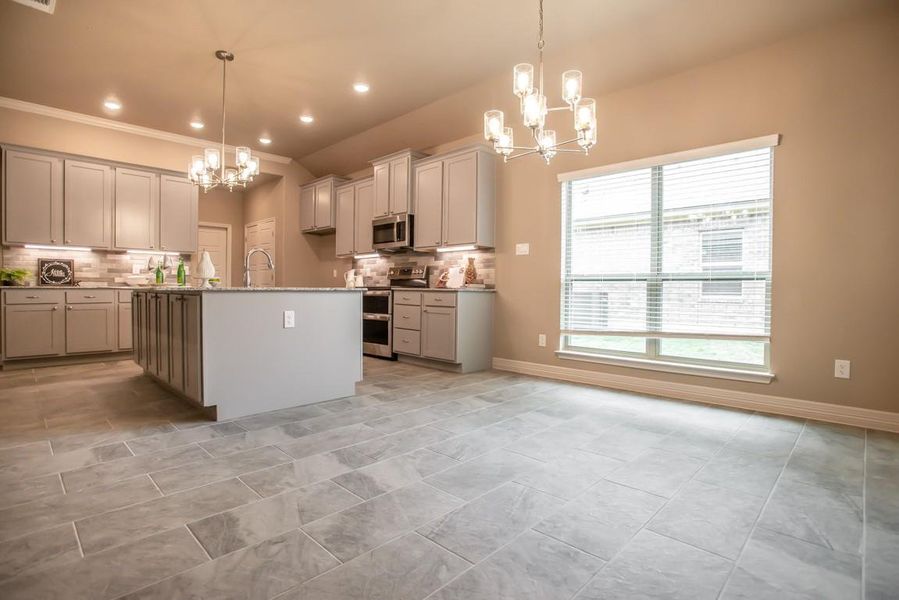 Kitchen with an inviting chandelier, decorative backsplash, stainless steel appliances, and a wealth of natural light