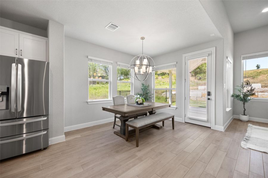 Enjoy a dedicated dining space with light wood-style flooring and a statement chandelier, perfectly positioned between the kitchen and living room. Large windows provide natural light and serene views of the outdoors—ideal for everyday meals or entertaining.