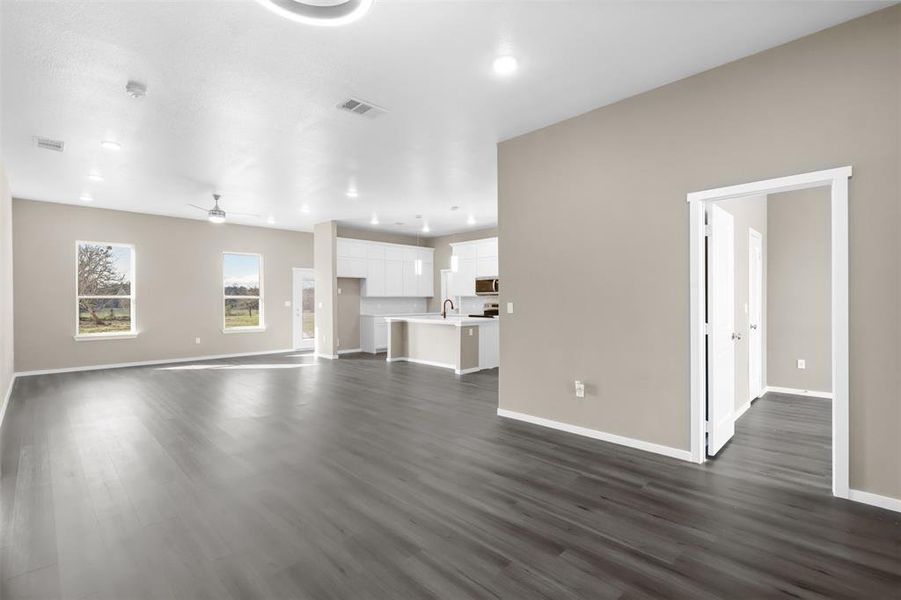 Unfurnished living room featuring ceiling fan, sink, and dark hardwood / wood-style flooring