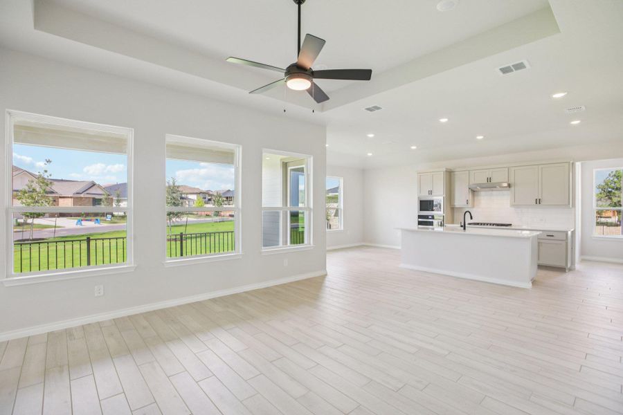 Unfurnished living room featuring recessed lighting, light wood-style floors, ceiling fan, and a raised ceiling
