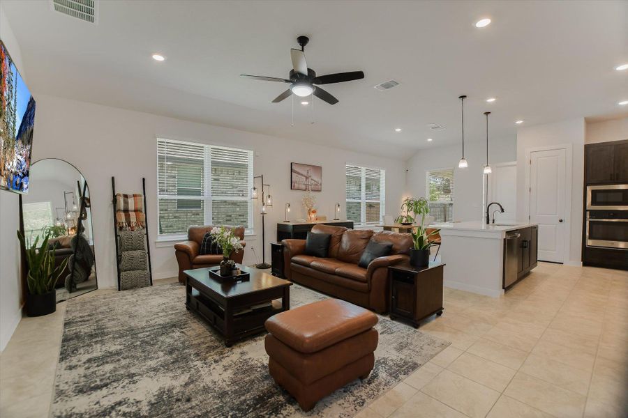 An open-concept living area with tile flooring seamlessly connects to a modern kitchen, creating an inviting atmosphere. An open-concept living area with tile flooring seamlessly connects to a modern kitchen, creating an inviting atmosphere.