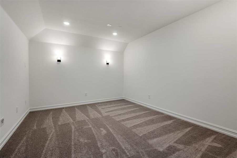 Carpeted empty room featuring vaulted ceiling