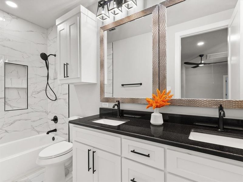 Bathroom featuring a dual vanity with undermount sinks, black countertops, and white shaker-style cabinetry Bathroom featuring a dual vanity with undermount sinks, black countertops, and white shaker-style cabinetry