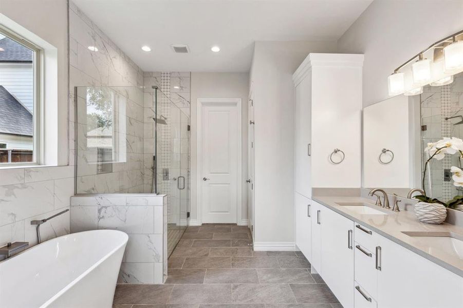 Freestanding soaking tub and glass enclosed shower.