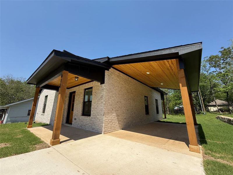 View of front of house with a front yard, brick siding, a carport, and driveway View of front of house with a front yard, brick siding, a carport, and driveway