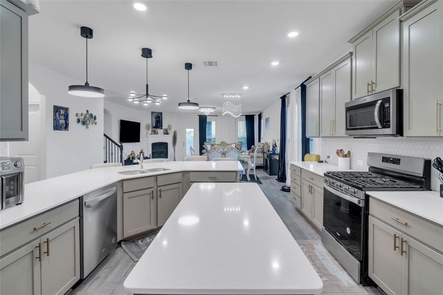 Kitchen featuring appliances with stainless steel finishes, a kitchen island, gray cabinetry, and sink