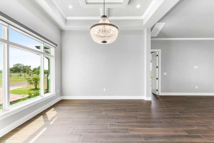 Empty room with a chandelier, wood finish floors, ornamental molding, a raised ceiling, and recessed lighting Empty room with a chandelier, wood finish floors, ornamental molding, a raised ceiling, and recessed lighting