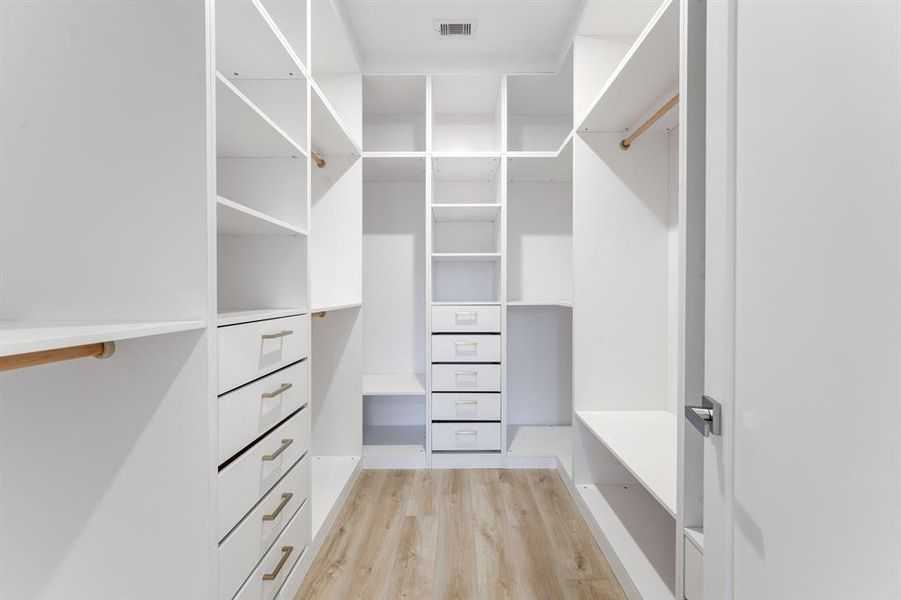 Luxurious custom built, walk-in closet with custom cabinetry, drawers, and gold accented hardware.