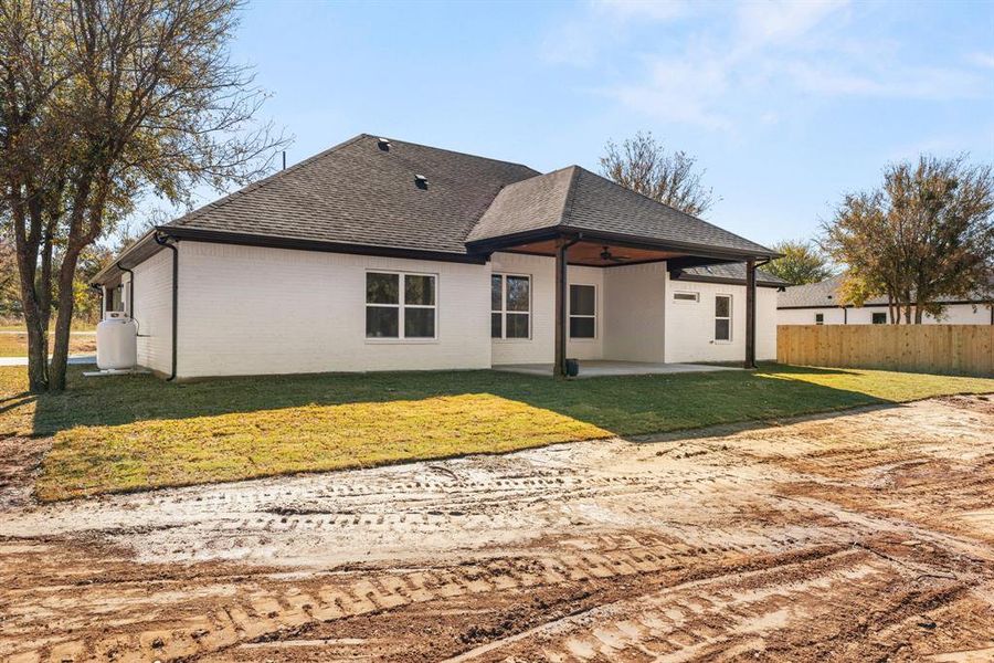 Back of property featuring a patio, a yard, roof with shingles, brick siding, and a ceiling fan