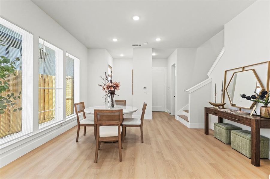Dining space featuring light wood-type flooring, recessed lighting, and stairs Dining space featuring light wood-type flooring, recessed lighting, and stairs