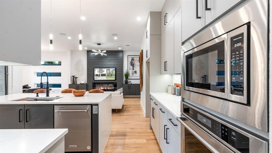 Kitchen featuring a fireplace, light wood-type flooring, stainless steel appliances, sink, and ceiling fan