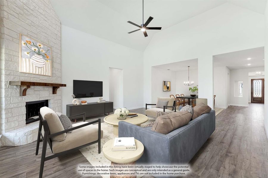 Living room with vaulted ceiling, stone fireplace, hardwood floors, and open view to dining area