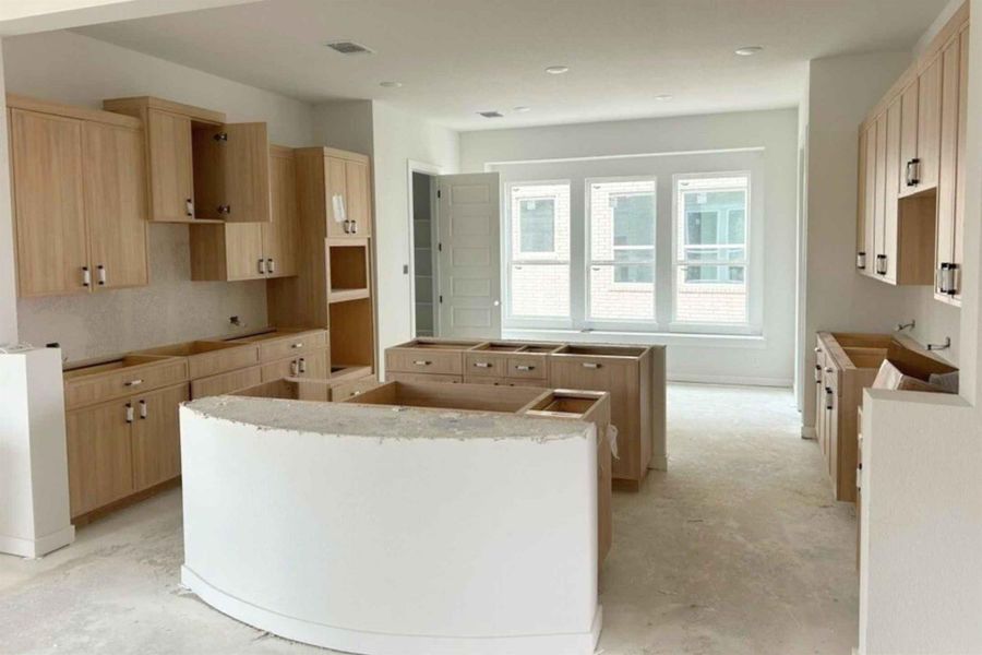 Kitchen with a kitchen island, light wood finish cabinetry, and unfinished concrete floors