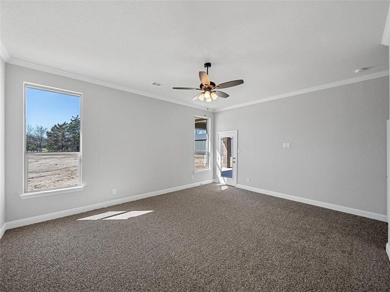 Prior listing photo. Property remains accurate - Unfurnished room with a ceiling fan, dark carpet, and ornamental molding
