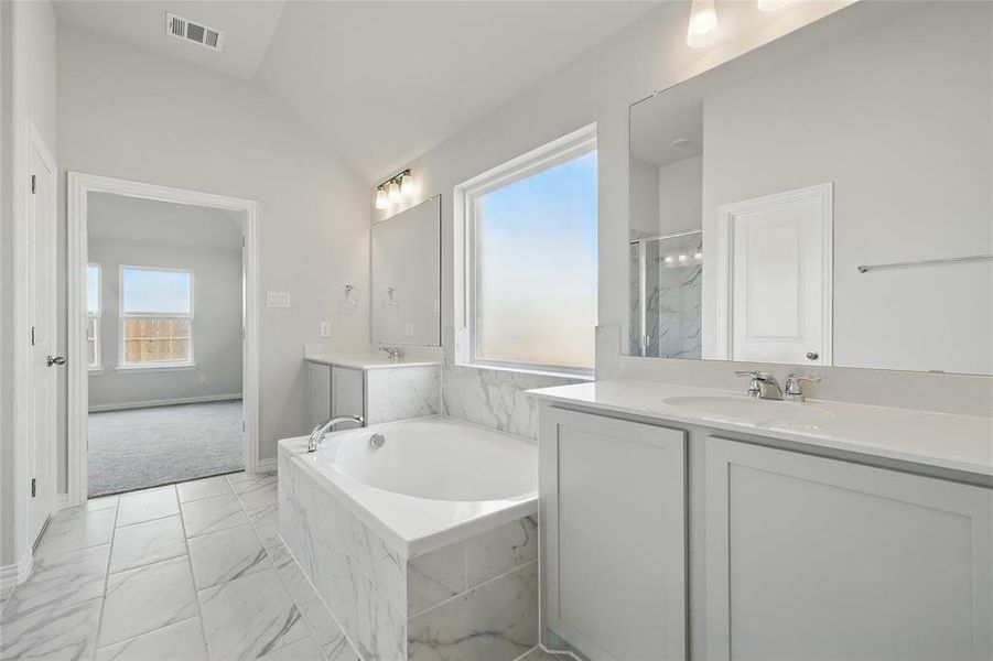 Full bath with vaulted ceiling, a bath, marble finish floors, vanity, and a marble finish shower Full bath with vaulted ceiling, a bath, marble finish floors, vanity, and a marble finish shower