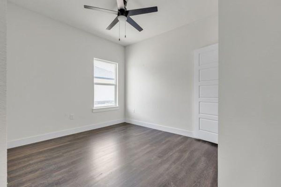Empty room with dark wood-style floors and ceiling fan