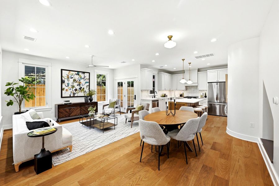 An open-concept living space with lustrous wood flooring flows seamlessly into a well-appointed kitchen. An open-concept living space with lustrous wood flooring flows seamlessly into a well-appointed kitchen.