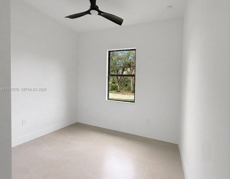 Bright interior room featuring a matte black ceiling fan, recessed lighting, and light-toned tile flooring