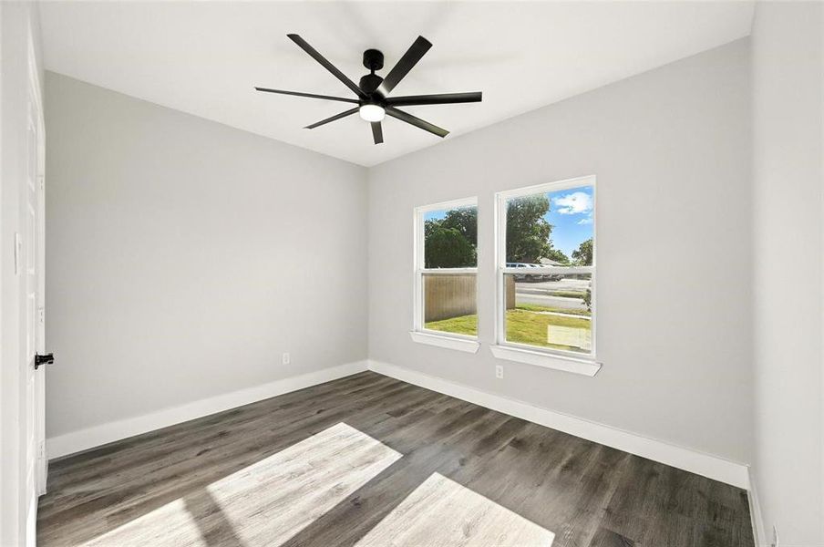 Empty room with dark wood-type flooring and ceiling fan Empty room with dark wood-type flooring and ceiling fan