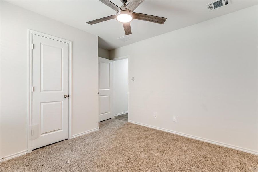 Neutral-toned carpeting extends throughout the room, complemented by white painted walls and baseboards Neutral-toned carpeting extends throughout the room, complemented by white painted walls and baseboards