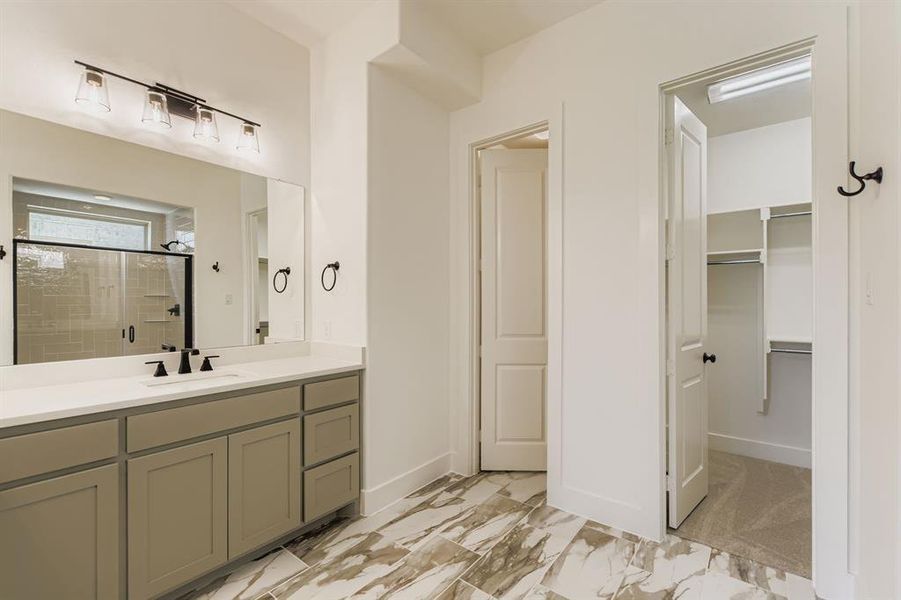Full bathroom with a shower stall, vanity, a walk in closet, and marble finish flooring Full bathroom with a shower stall, vanity, a walk in closet, and marble finish flooring