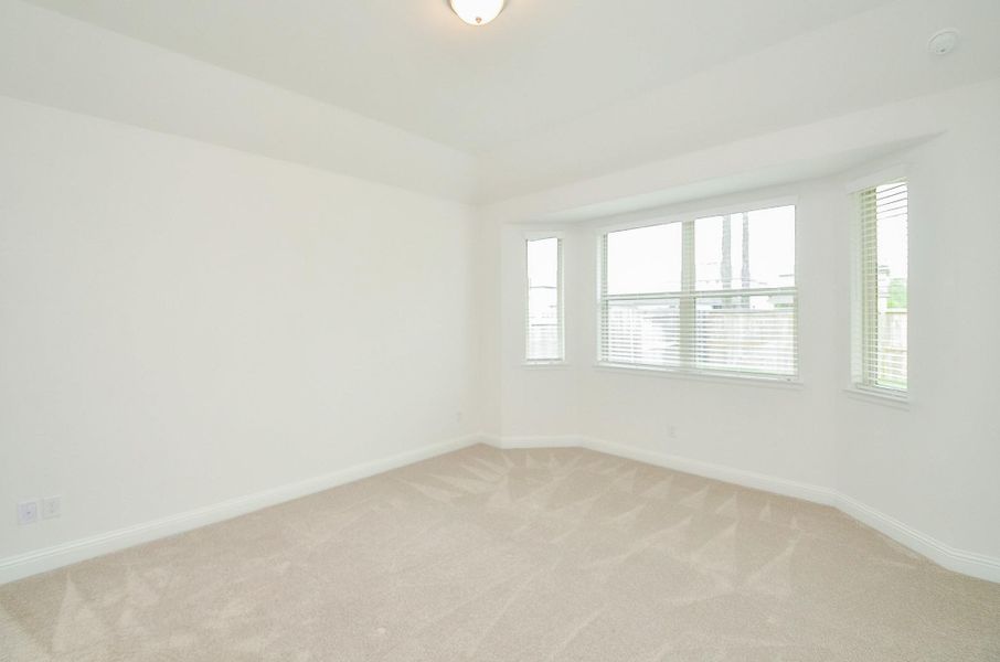 This bright and airy Primary Bedroom with light carpeting, neutral walls, and a large bay window providing plenty of natural light.