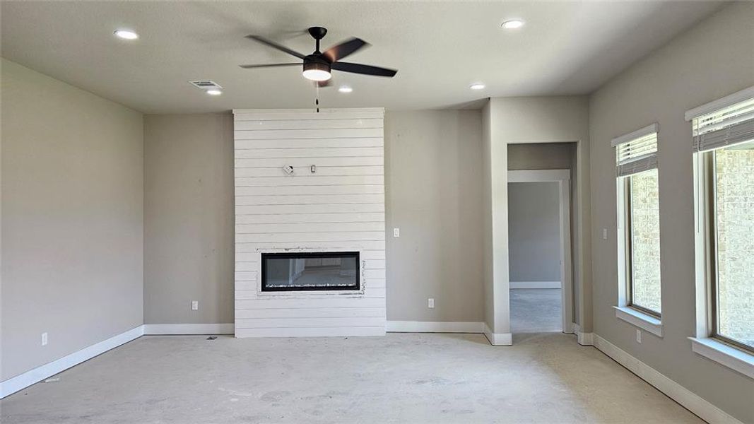 Unfurnished living room featuring a fireplace, ceiling fan, and a healthy amount of sunlight