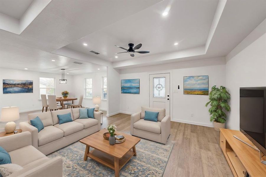 Living room featuring light hardwood / wood-style floors, a raised ceiling, and ceiling fan