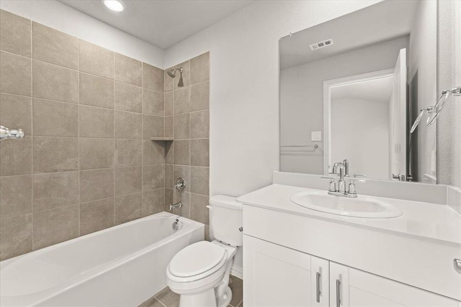 Full bathroom featuring tile patterned flooring, vanity, toilet, and tiled shower / bath