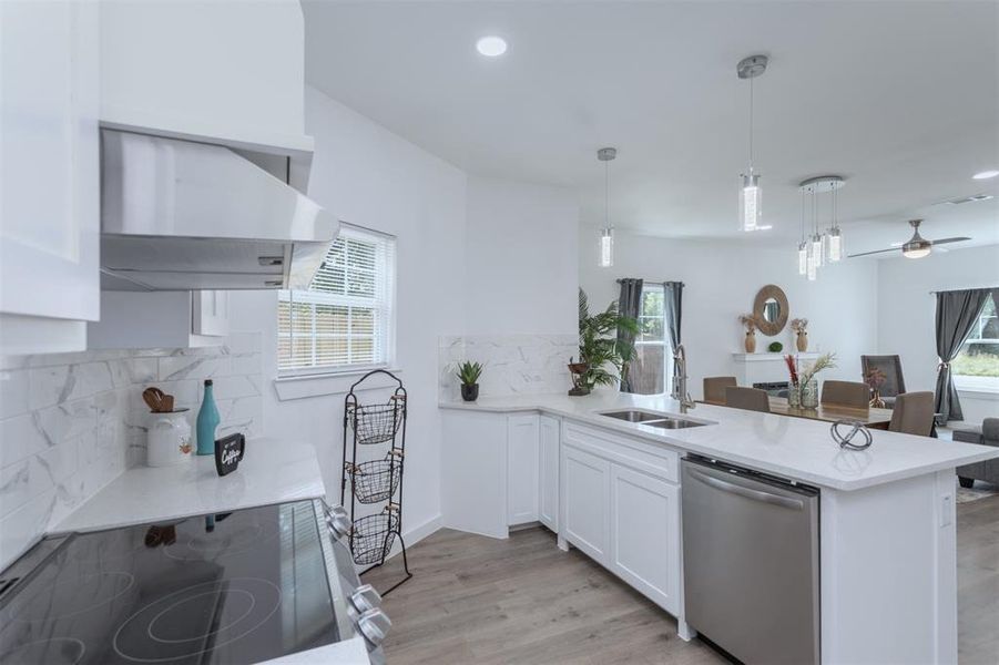 Kitchen with pendant lighting, white cabinets, kitchen peninsula, and stainless steel dishwasher